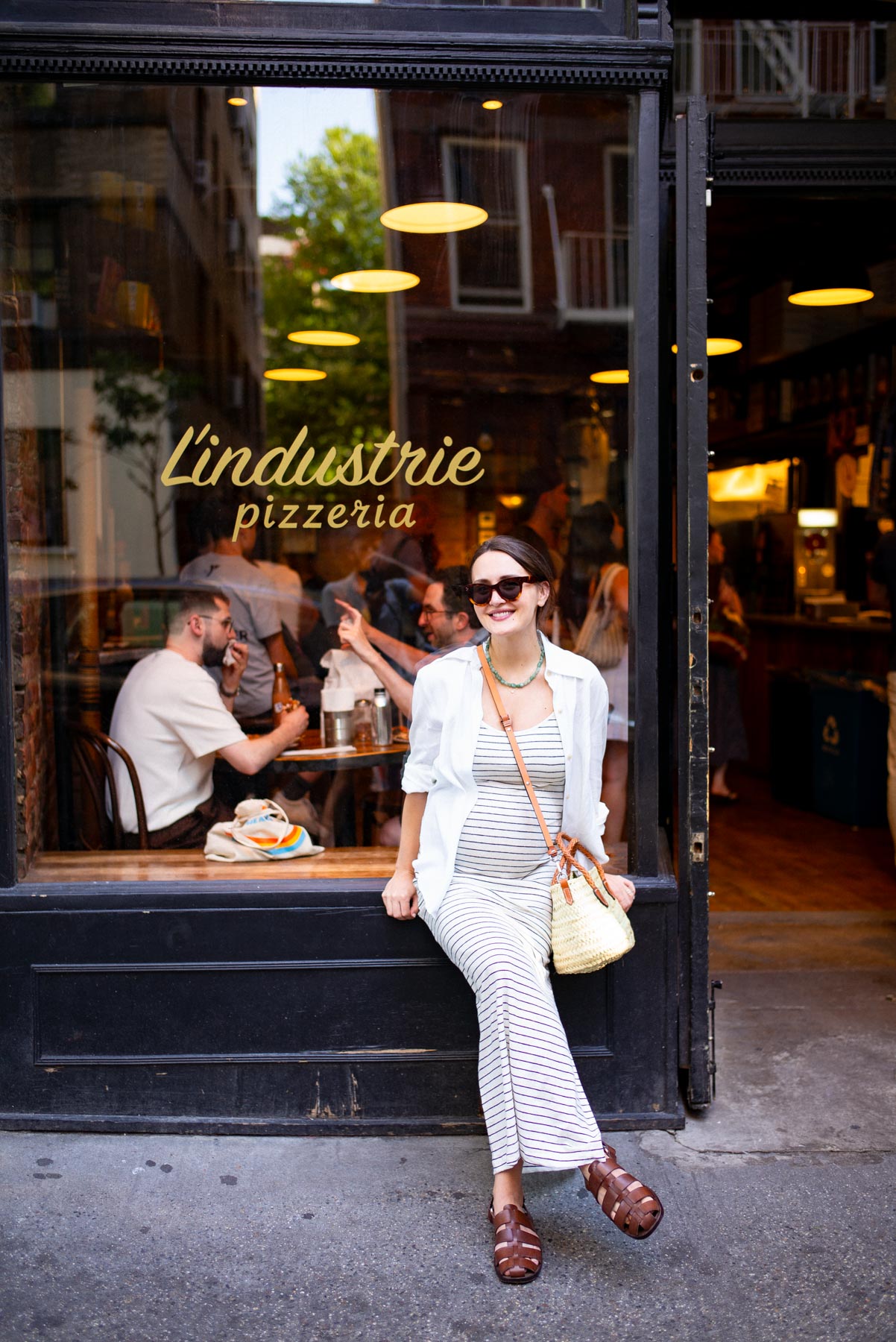 A woman poses on the windowsill outside L'Industrie Pizzeria.