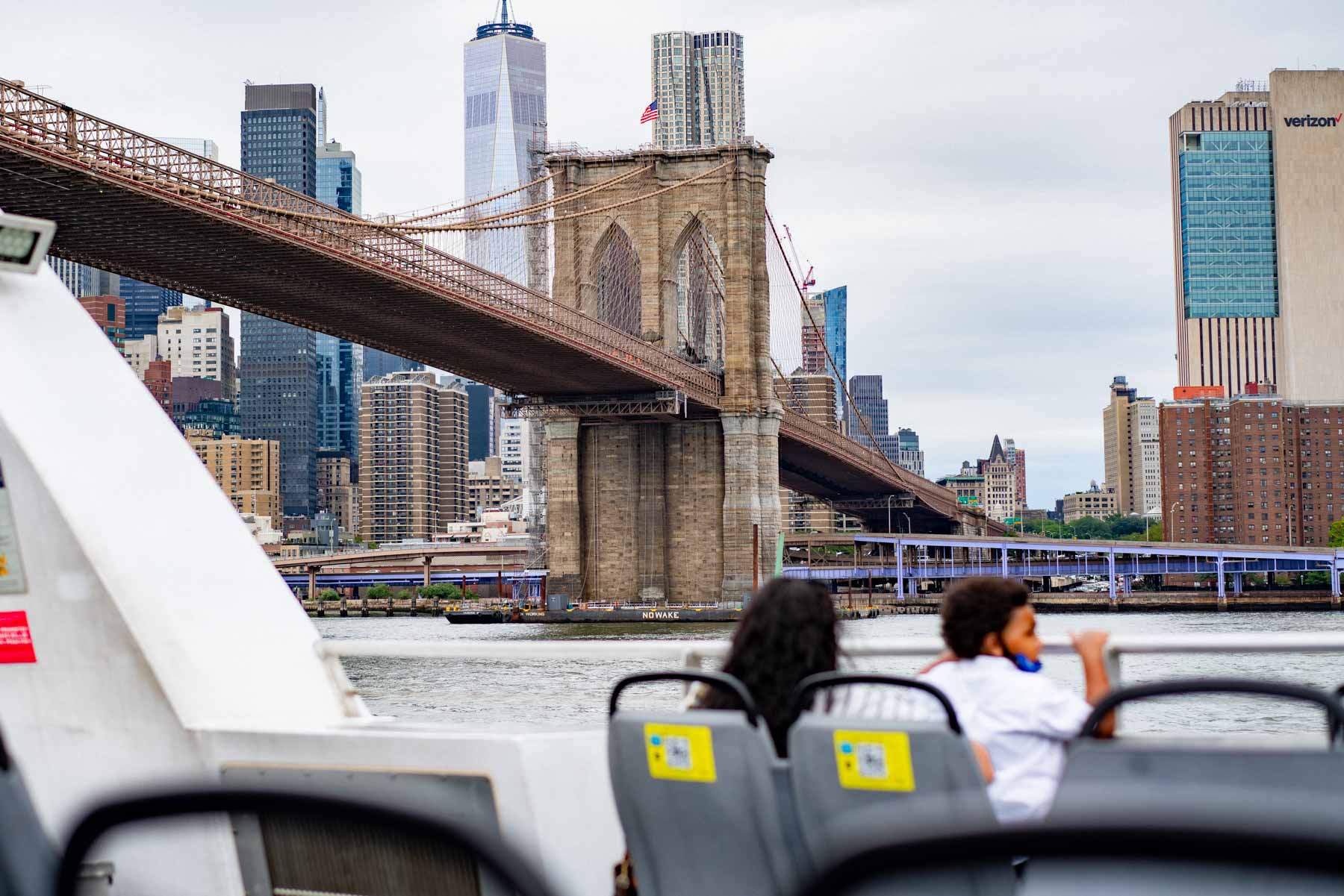 child riding ferry in NYC, brooklyn bridge in background