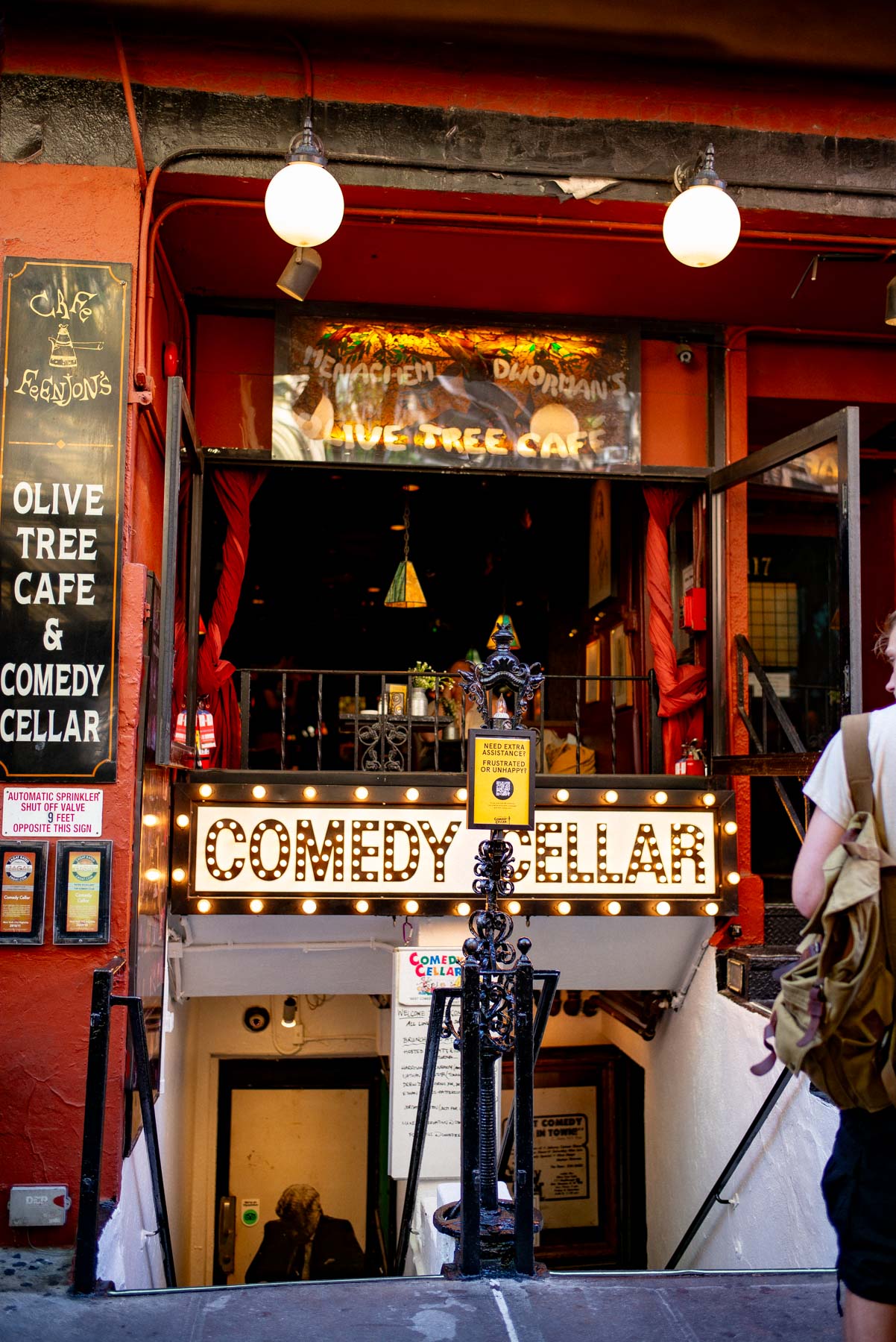 The entrance to the Comedy Cellar with its lit marquee sign and staircase down to the club.