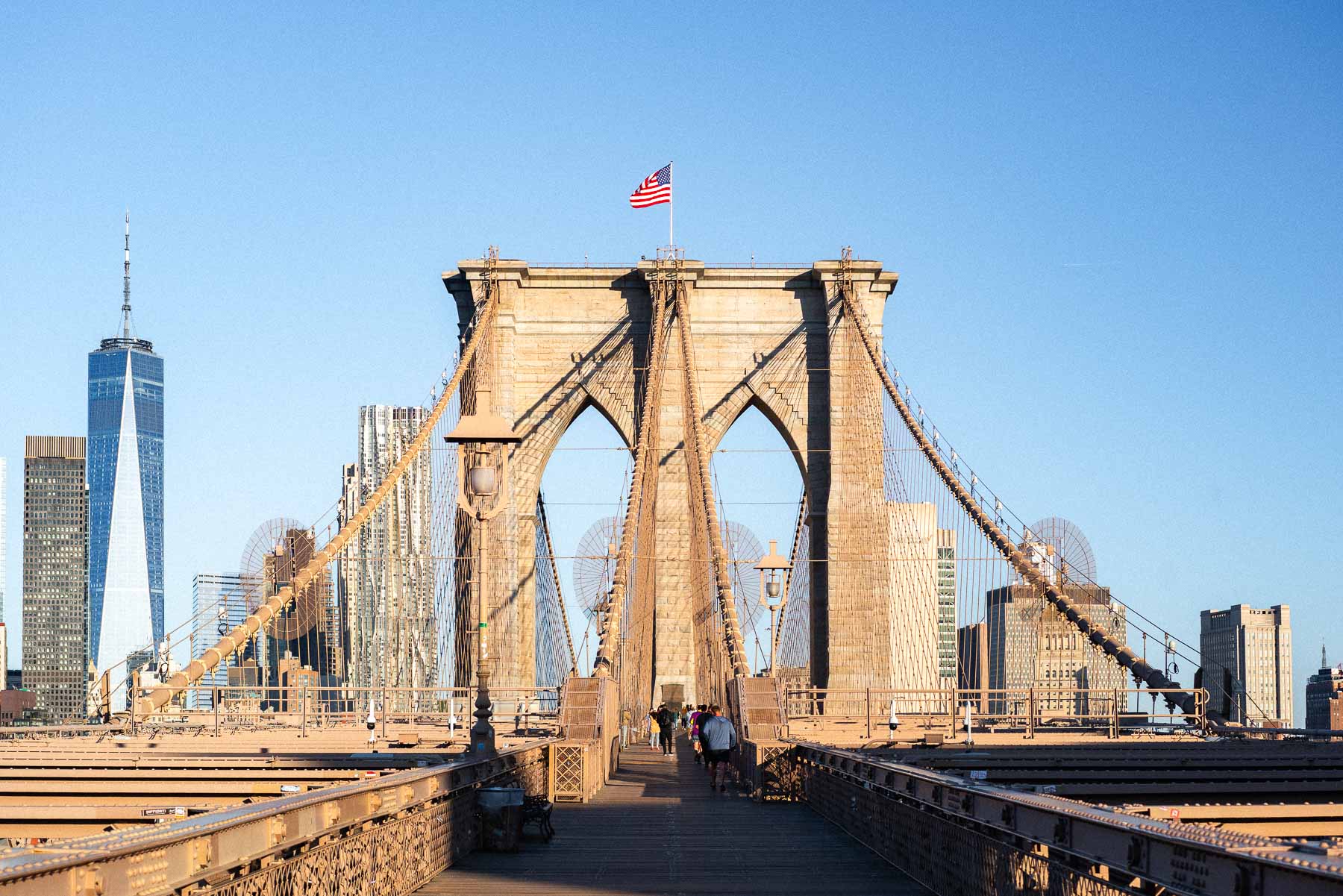The pedestrian walkway on the Brooklyn Bridge leading toward the Manhattan skyline on a clear day