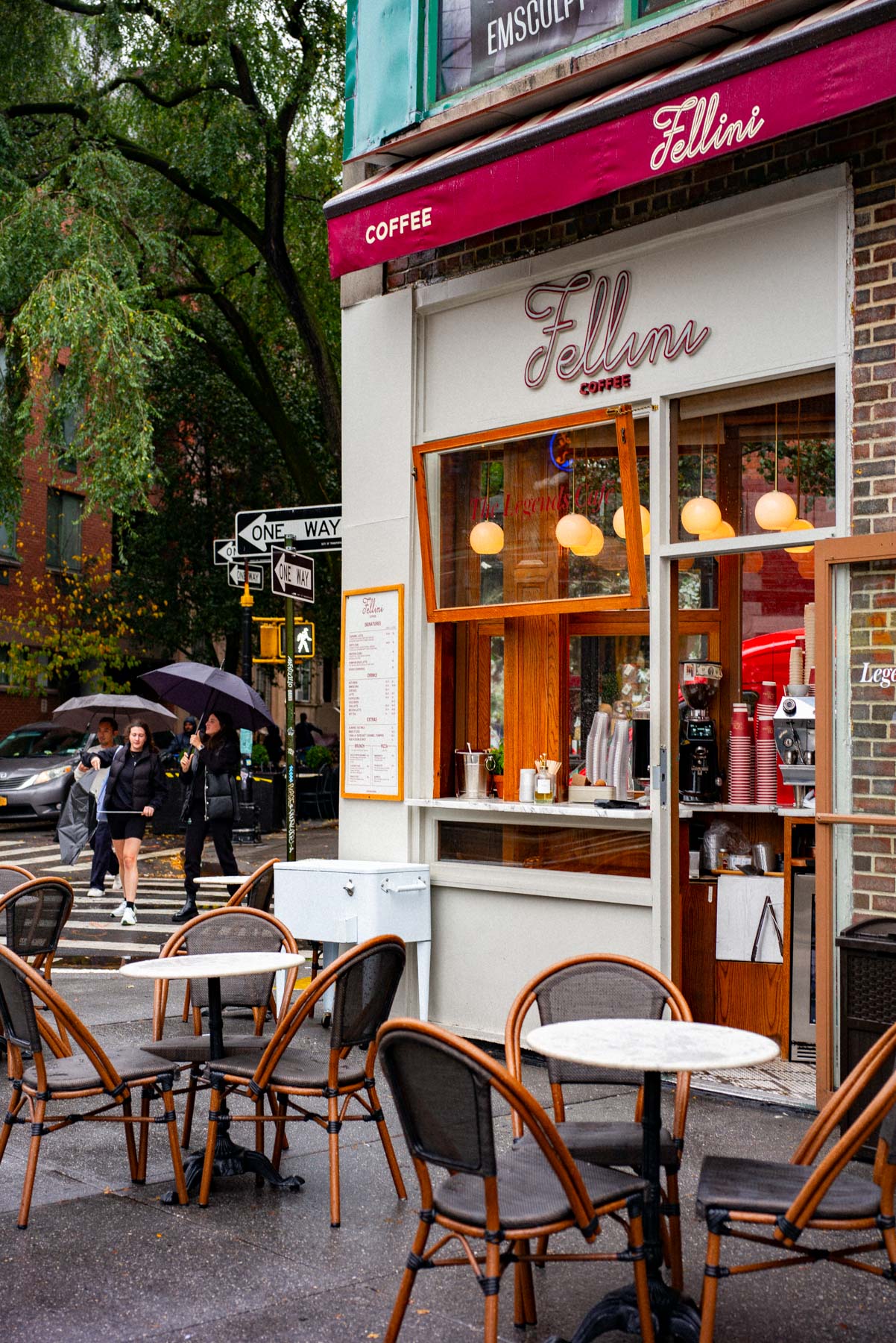 Everyday New York City sidewalk scene with pedestrians walking past storefronts along a busy block
